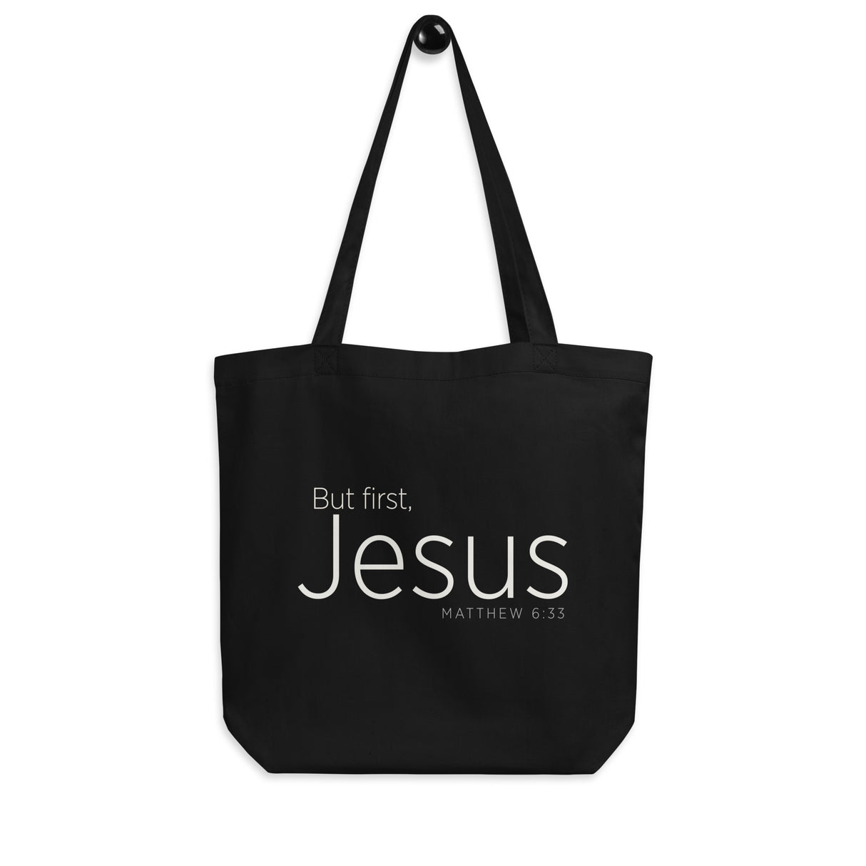 "But first, Jesus Matthew 6:33" in cream white lettering on a black Eco tote bag