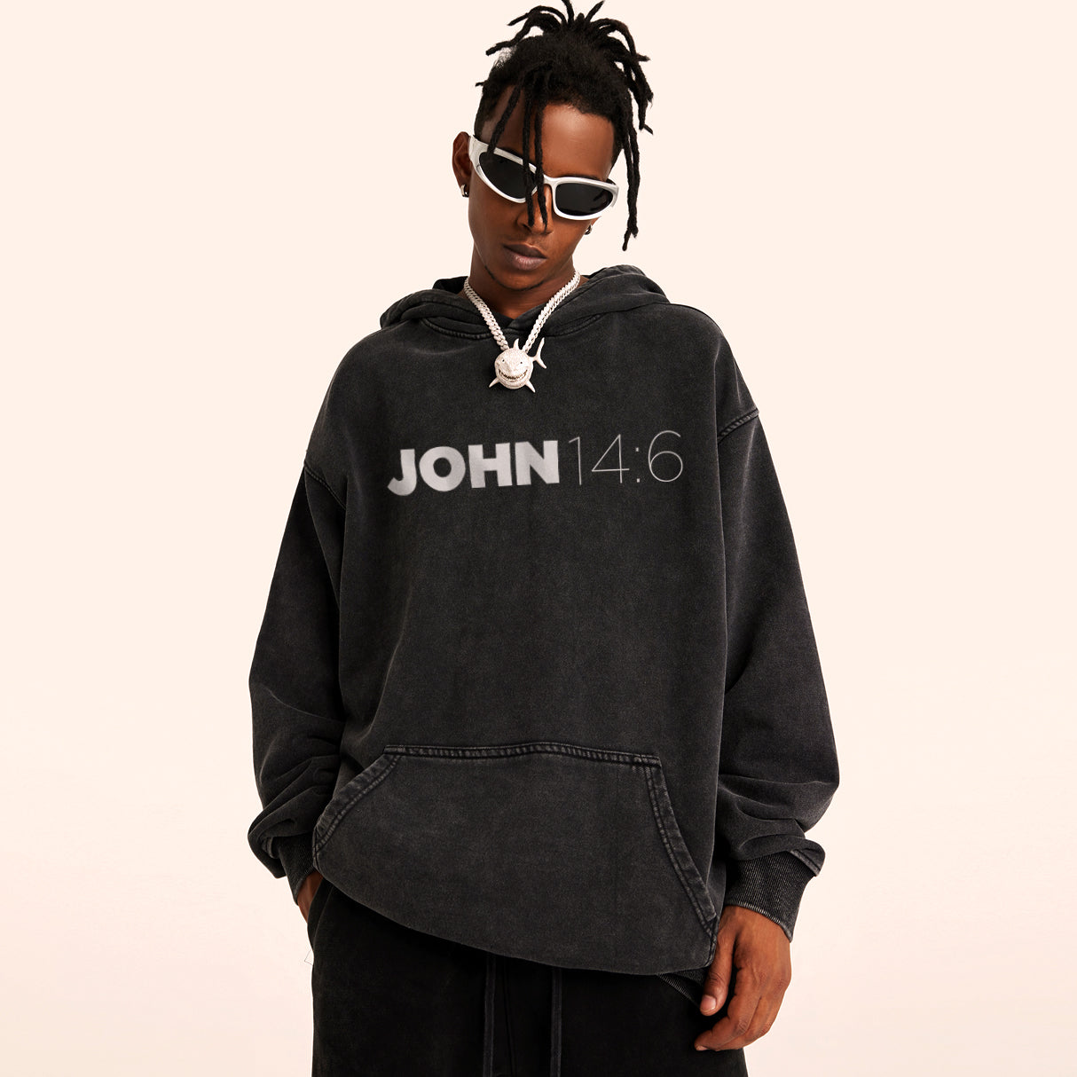 Man wearing a black oversized retro hoodie with "JOHN 14:6" in white ink. Cream white backdrop.