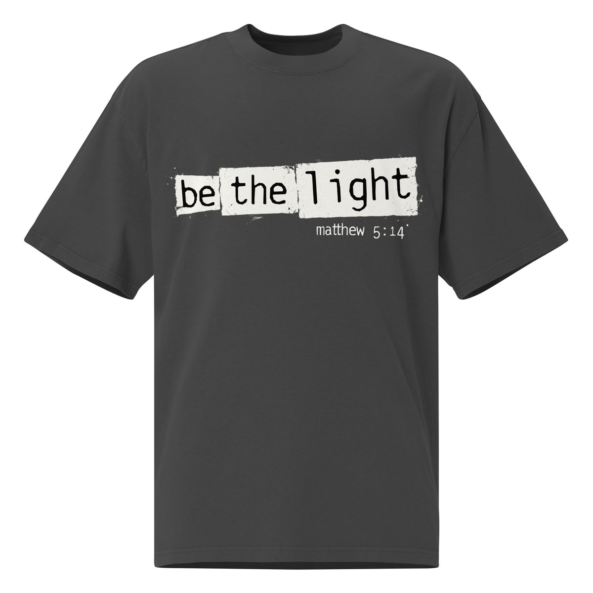 Front view of a Faded Black oversized tee featuring Be the Light in black typewriter lettering over distressed cream panels, Matthew 5:14