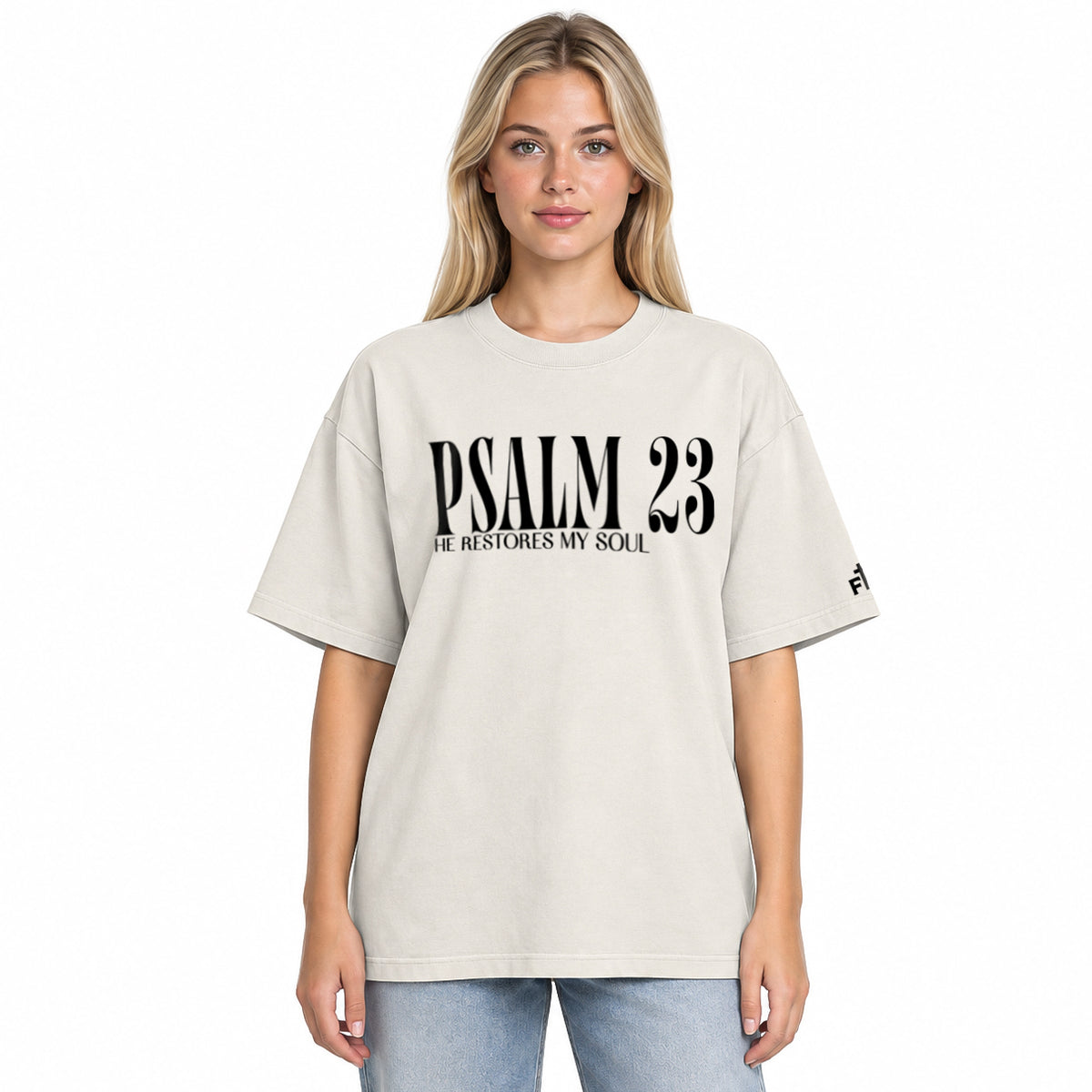 Front view of a faded bone oversized tee featuring black PSALM 23 lettering with He Restores My Soul underneath and a small Faith Mode logo on the sleeve.