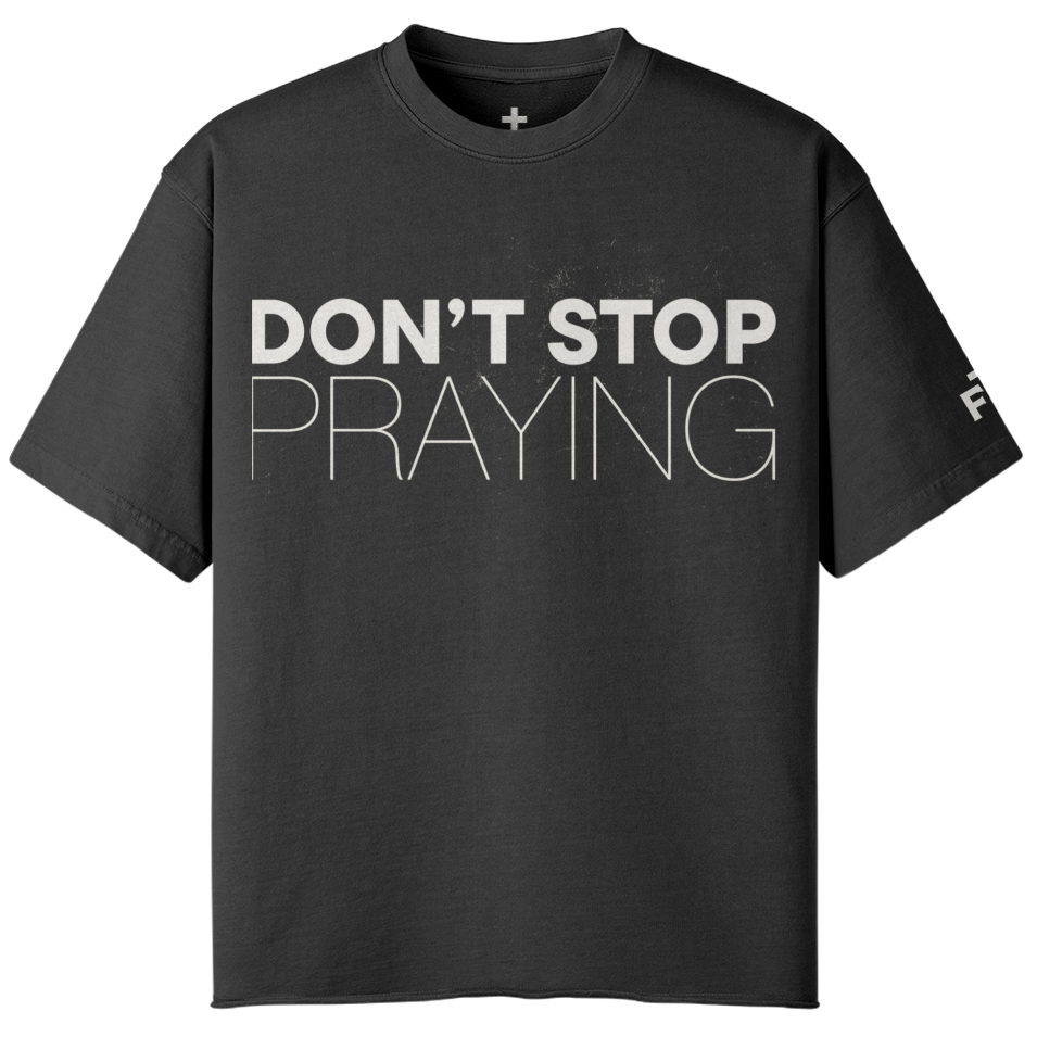 Black t-shirt with 'DON'T STOP PRAYING' text on a white background