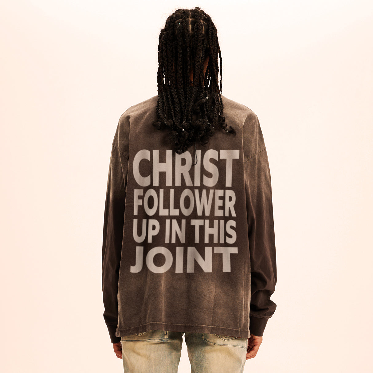 Person wearing a brown sweatshirt with text on the back against a beige background