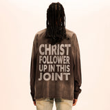 Person wearing a brown sweatshirt with text on the back against a beige background