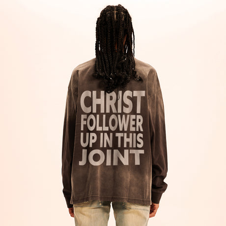 Person wearing a brown sweatshirt with text on the back against a beige background