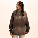 Person wearing a brown sweatshirt with 'MT 10:32' text on a beige background