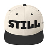 Beige cap with black 'STILL' text on a white background