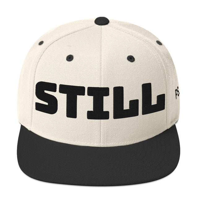 Beige cap with black 'STILL' text on a white background