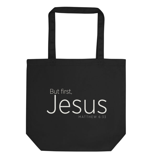 "But first, Jesus Matthew 6:33" in cream white lettering on a black Eco tote bag, flat view