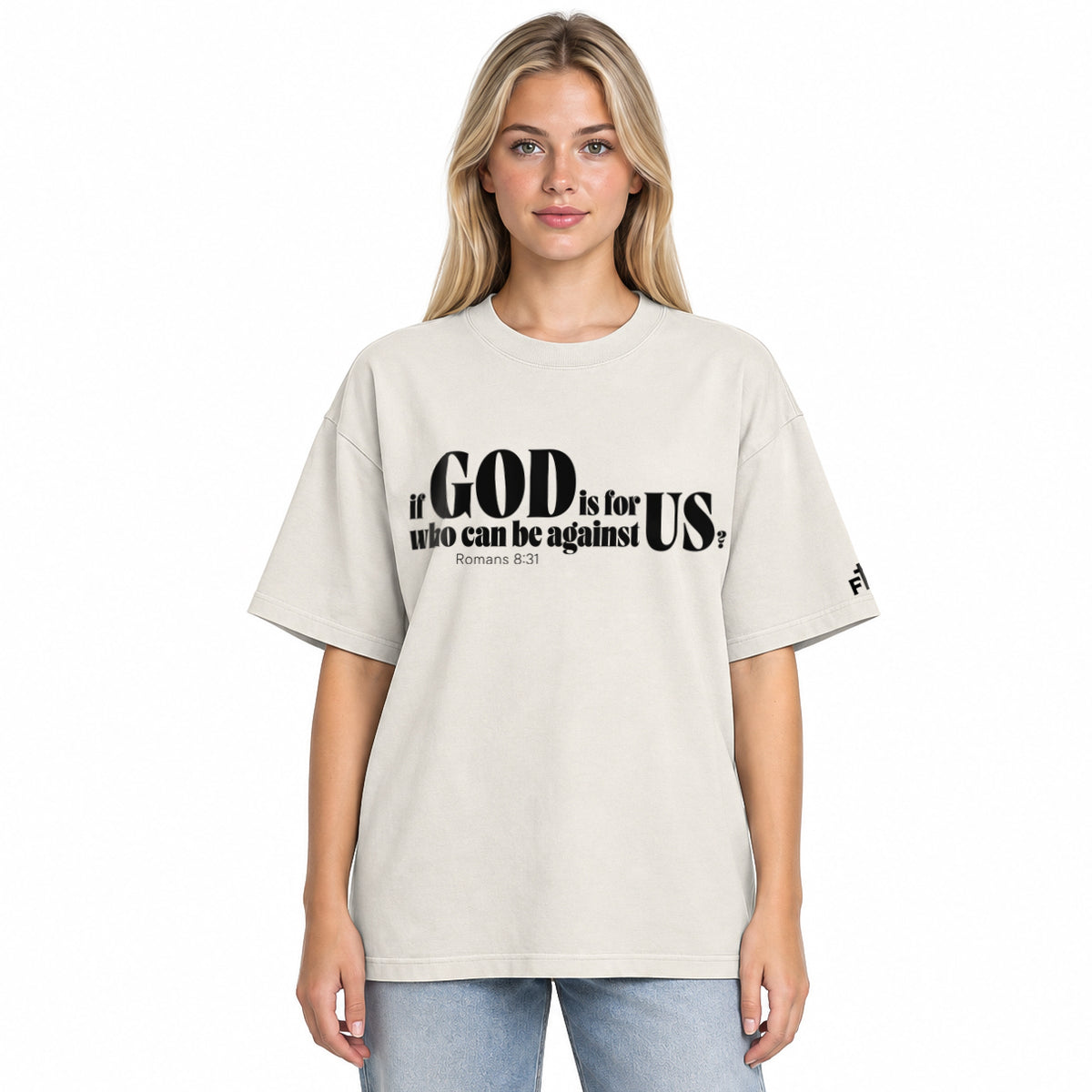 Front view of a faded bone oversized tee featuring black If God Is for Us Who Can Be Against Us lettering, Romans 8:31, and a small Faith Mode sleeve logo.