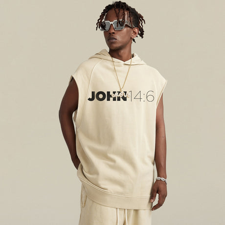 Person wearing a beige sleeveless hoodie with 'JOHN 14:6' text on a plain background