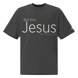 Front view of a Faded Black oversized tee featuring cream But First, Jesus lettering, Matthew 6:33, and a small Faith Mode logo on the left sleeve.
