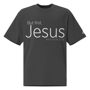 Front view of a Faded Black oversized tee featuring cream But First, Jesus lettering, Matthew 6:33, and a small Faith Mode logo on the left sleeve.