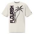 Front view of a faded bone oversized tee with dark plum vertical FLOURISH and Psalm 92:12 lettering, a palm tree graphic across the front, and a small logo on the sleeve.