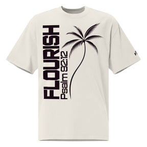 Front view of a faded bone oversized tee with dark plum vertical FLOURISH and Psalm 92:12 lettering, a palm tree graphic across the front, and a small logo on the sleeve.