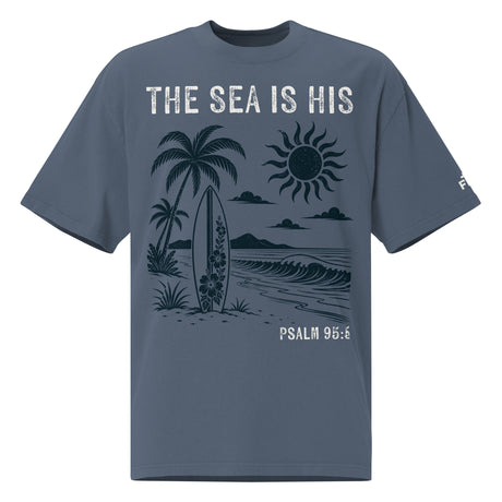 Front view of a Faded Indigo oversized tee featuring The Sea Is His, Psalm 95:5, palm trees, a surfboard, sun, ocean waves, and a small sleeve logo.