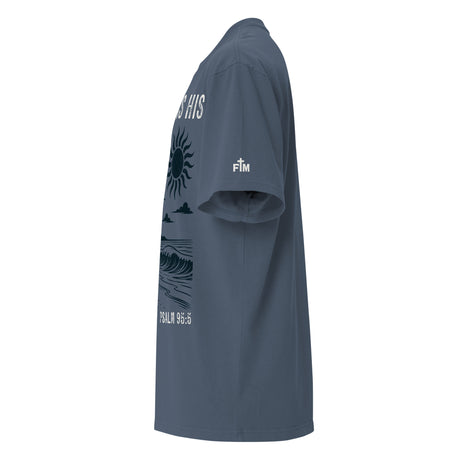 Side view of a Faded Indigo oversized tee featuring The Sea Is His, Psalm 95:5, palm trees, a surfboard, sun, ocean waves, and a small sleeve logo.