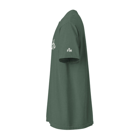 A dark green short-sleeve t-shirt shown from a side profile view against a plain white background. The shirt features white script lettering on the upper chest and a small white 'FM' (Faith Mode) logo on the left sleeve.