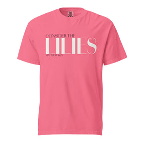 A pink short-sleeve crewneck t-shirt with a white graphic text print reading 'CONSIDER THE LILIES' and 'MATTHEW 6:28' underneath, displayed on a solid white background.