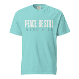 A light turquoise crewneck t-shirt with the text 'PEACE, BE STILL' and 'MARK 4:39' printed on the chest in a pale cream and dark gray font, shown against a plain white background.