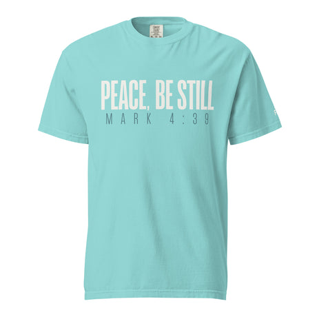 A light turquoise crewneck t-shirt with the text 'PEACE, BE STILL' and 'MARK 4:39' printed on the chest in a pale cream and dark gray font, shown against a plain white background.