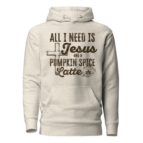 A light heather gray pullover hoodie with a dark brown graphic print on the front. The graphic features a cross, the text 'ALL I NEED IS Jesus AND A PUMPKIN SPICE Latte' in stylized fonts, and a small coffee cup illustration.