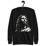 Black unisex sweatshirt featuring a large distressed cream-white artistic portrait of Jesus looking upward. Shown with hanger.