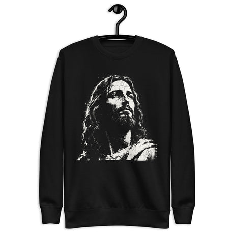 Black unisex sweatshirt featuring a large distressed cream-white artistic portrait of Jesus looking upward. Shown with hanger.