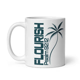 White glossy coffee mug with a left-side handle, featuring dark teal vertical FLOURISH lettering, Psalm 92:12, and a palm tree illustration.