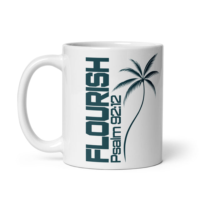 White glossy coffee mug with a left-side handle, featuring dark teal vertical FLOURISH lettering, Psalm 92:12, and a palm tree illustration.