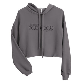 Front view of a Storm gray women’s crop hoodie with black “Be Strong and Courageous” Joshua 1:9 lettering, a drawstring hood, and long sleeves.