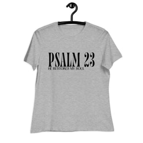 A light heather gray short-sleeve t-shirt hanging on a black hanger against a plain white background. The front of the shirt features the text 'PSALM 23' in a large black serif font, with 'HE RESTORES MY SOUL' printed underneath in a smaller black serif font.