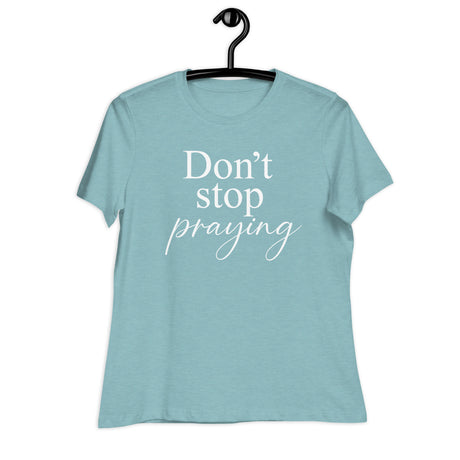 Light blue t-shirt with 'Don't stop praying' text on a hanger against a white background
