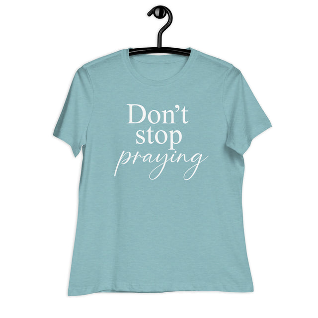 Light blue t-shirt with 'Don't stop praying' text on a hanger against a white background