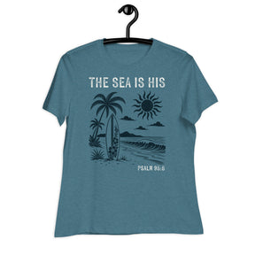 "The Sea is His" "Psalm 95:5" Printed in Cream white with a lightly distressed vintage 70s beach design in dark teal against a lighter teal women's shirt
