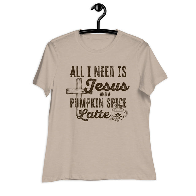 A beige short-sleeve t-shirt hanging on a black hanger against a white background, featuring a dark brown graphic print that reads 'ALL I NEED IS Jesus AND A PUMPKIN SPICE Latte' with a cross, coffee cup, and spice motif.